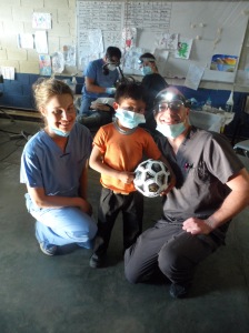 Dr. Marsh, Dr. Harper and Alberto, who had three teeth extracted, pose for a picture after Alberto received his prize, a soccer ball, for being the best patient of the day.
